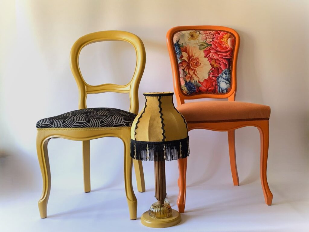 Zestaw odnowionych krzeseł w stylu retro z tapicerką w kwiaty i żółtym siedziskiem oraz stylowa lampa stołowa z Pracowni Kolorowanka