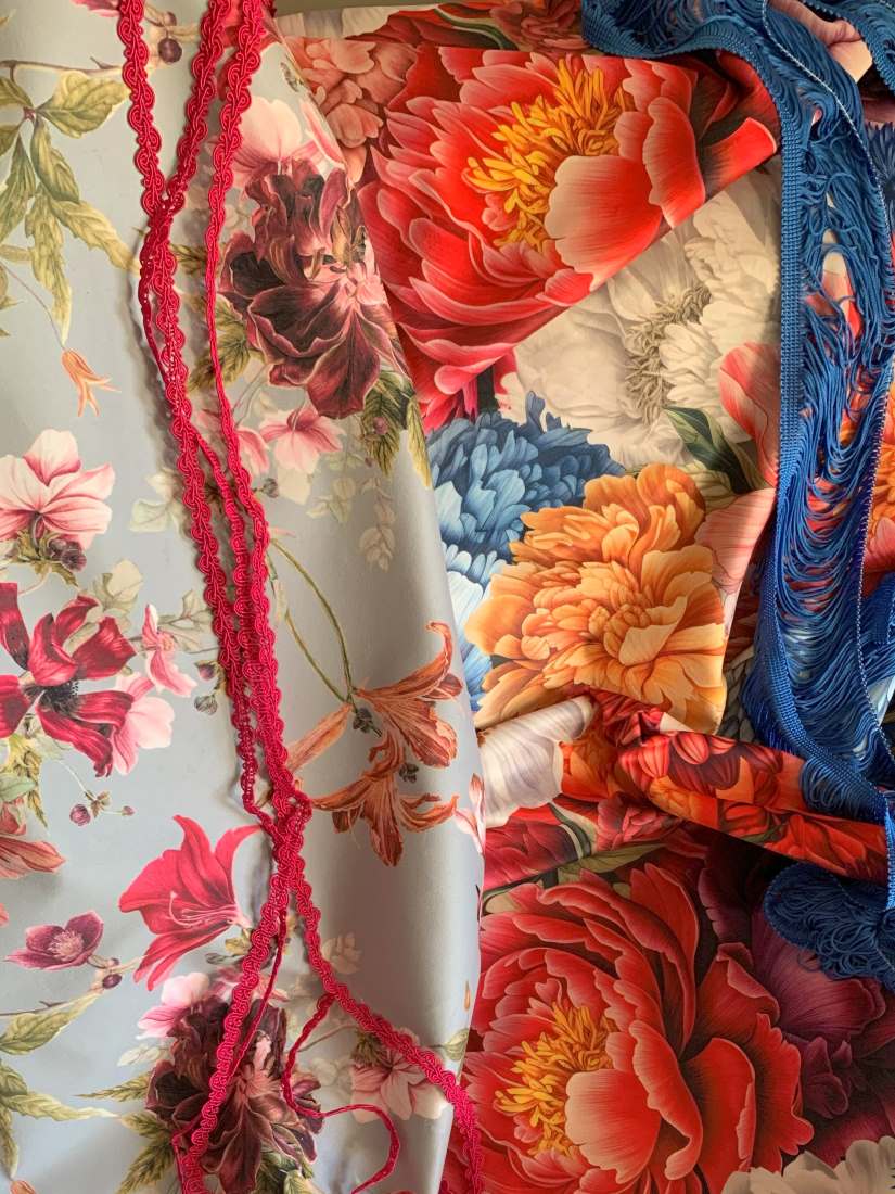 Zbliżenie na kolorowe tkaniny w stylu boho z motywem kwiatowym, zdobione dekoracyjnym sznurem i frędzlami