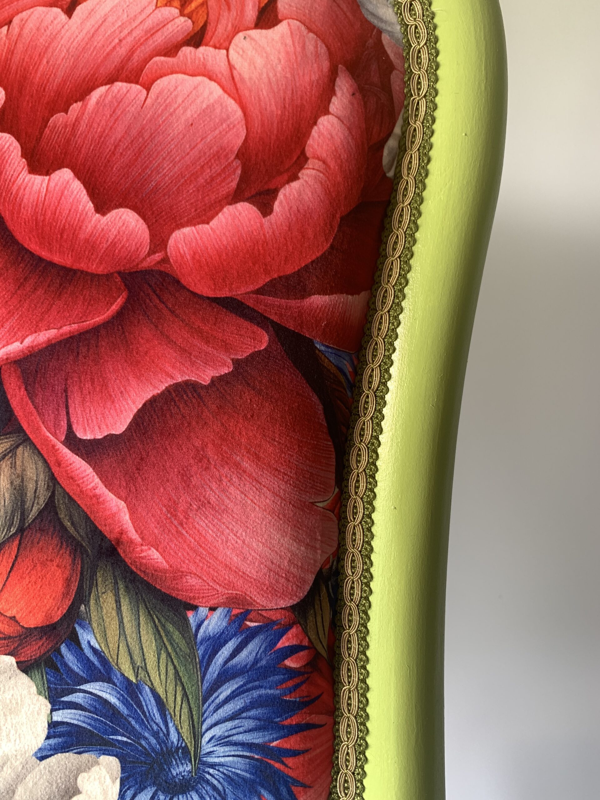 Zbliżenie na ozdobną pasmanterię i kwiatową tkaninę tapicerską na odnowionym krześle w stylu vintage