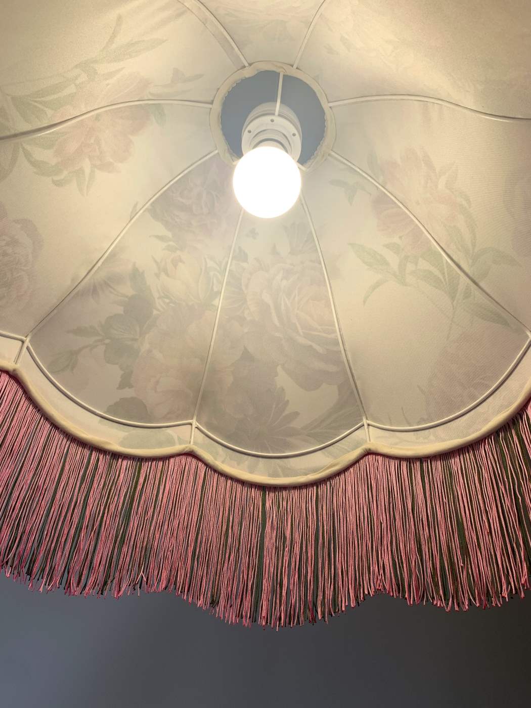Perspektywa od dołu na wnętrze klosza wiszącej lampy w stylu vintage z kwiatowym wzorem i frędzlami