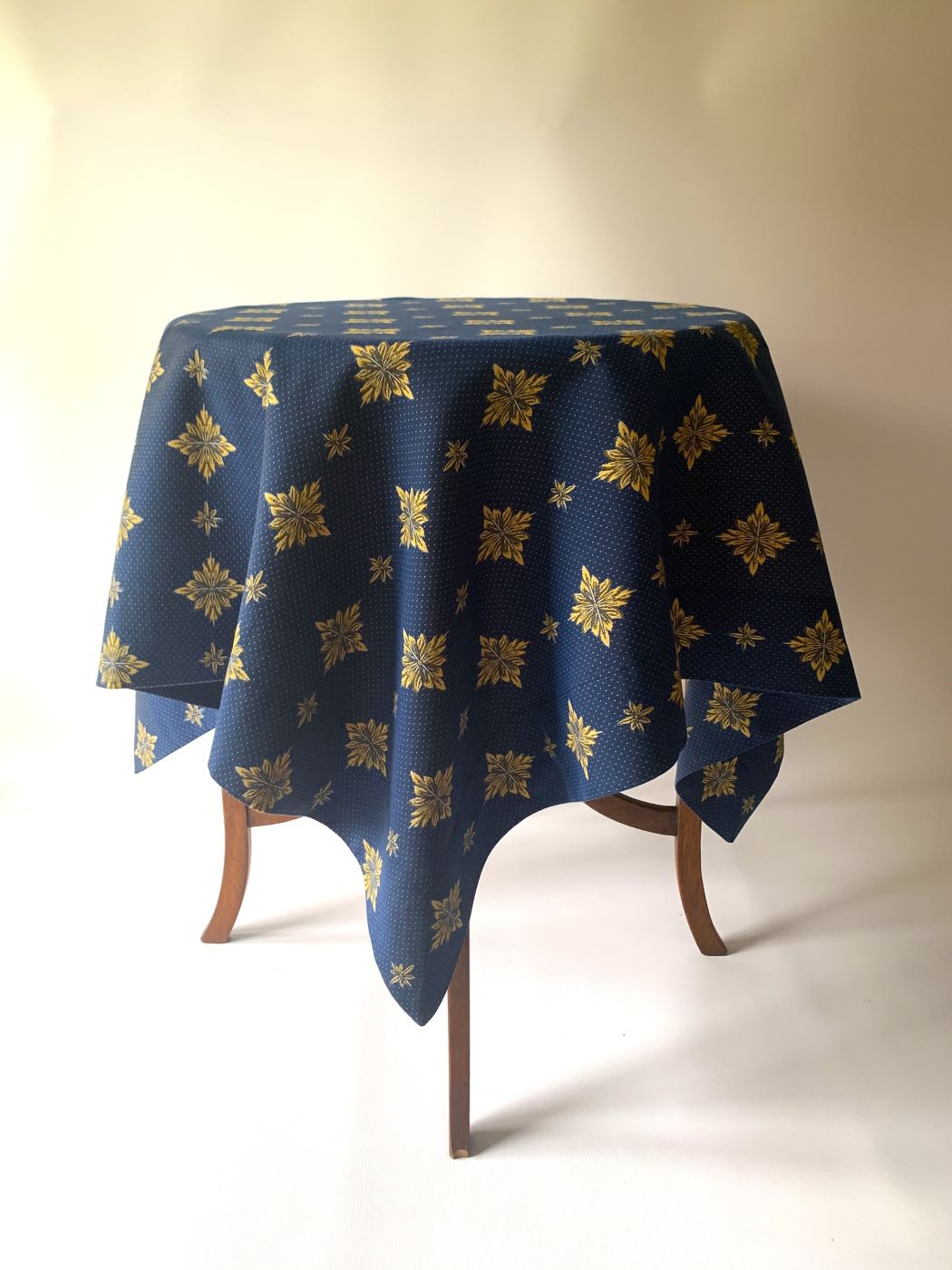 Elegancki granatowy obrus z ozdobnym złotym wzorem na okrągłym stole do jadalni