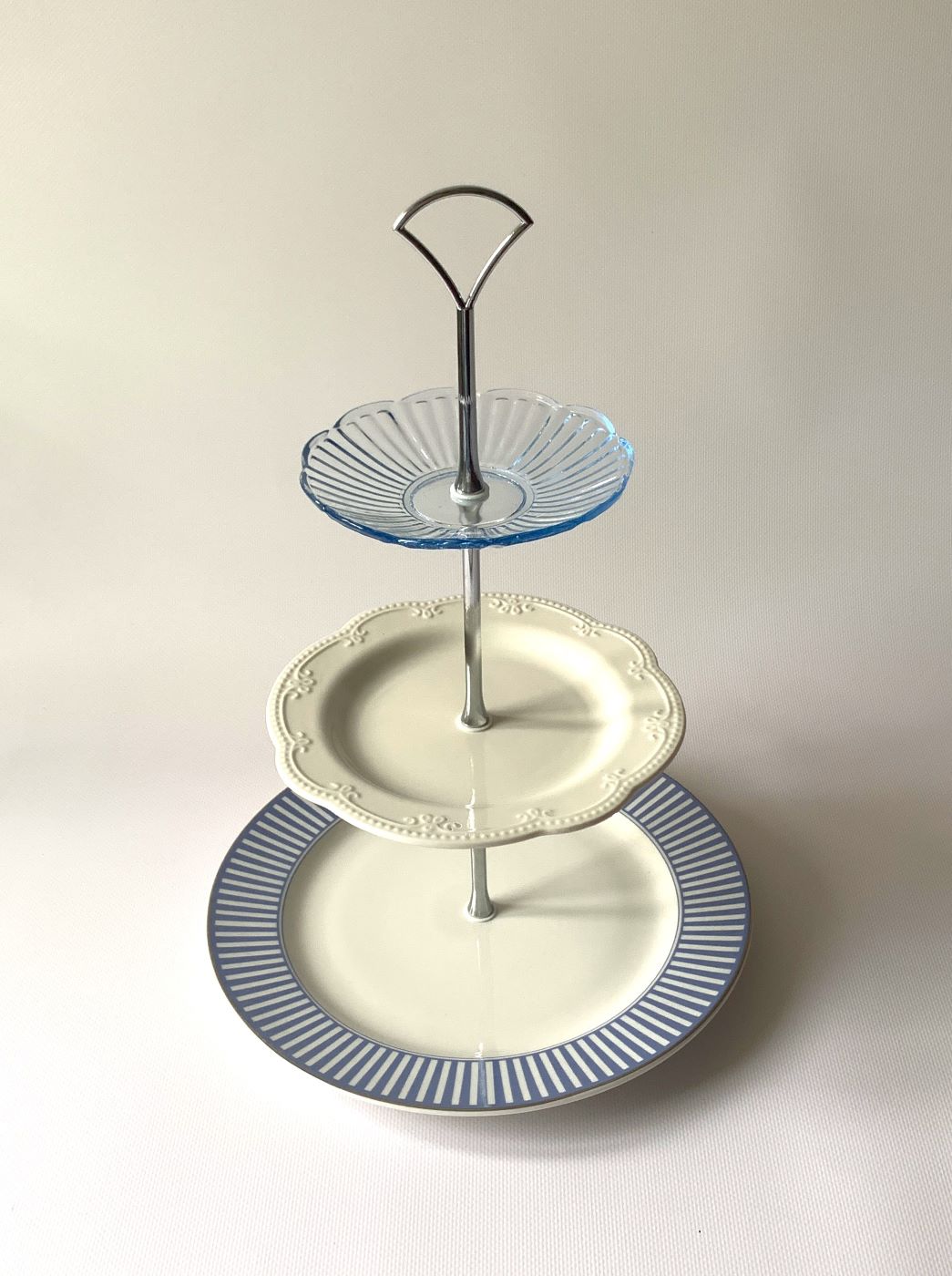 Elegancka trzypiętrowa patera na słodycze wykonana z kombinacji niebieskiego szkła oraz zdobionej białej porcelany