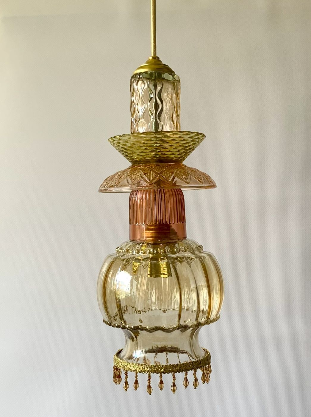 Lampa wisząca składająca się ze szklanych talerzyków i wazoników dołem zakończona szklanym kloszem. Kolory bursztynowo-miodowe.